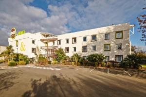 un gran edificio blanco con aparcamiento en B&B HOTEL Nantes Atlantis Le Zenith, en Saint-Herblain