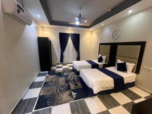 a bedroom with two beds and a checkered floor at خزامى ابها للشقق المخدومة in Abha