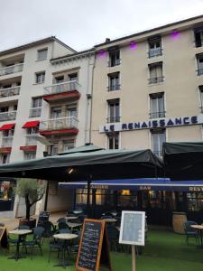 un hotel con mesas y sombrillas delante en Le Renaissance, en Aurillac
