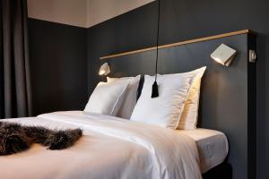 a bedroom with a bed with white sheets and pillows at Hotel Monsieur Ernest in Bruges