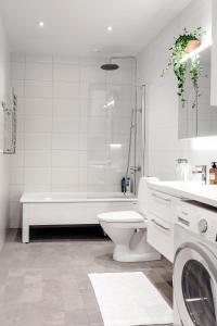 a white bathroom with a tub and a toilet at Stylish Waterfront Apt Stockholm in Stockholm +46 photos