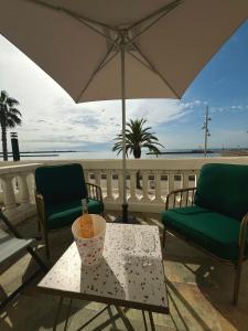 un tavolo con un ombrellone e una bevanda sopra di L'Hôtel De La Plage a Le Grau-du-Roi