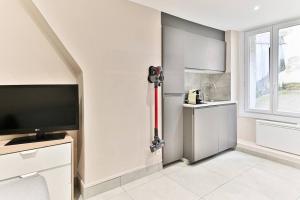 a white kitchen with a television and a window at Studio Confortable au cœur du Quartier Sentier in Paris +12 photos