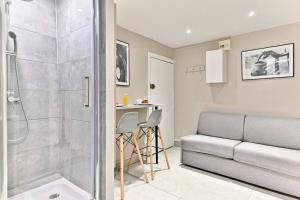 a bathroom with a walk in shower and a couch at Studio Confortable au cœur du Quartier Sentier in Paris