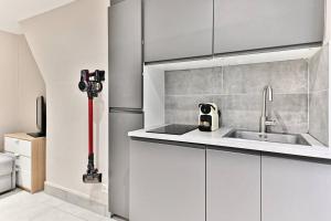 a kitchen with white cabinets and a sink at Studio Confortable au cœur du Quartier Sentier in Paris