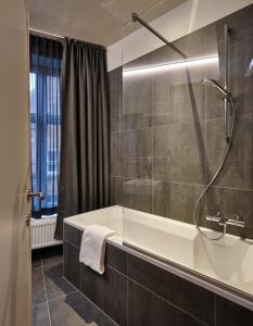 Das Bad ist mit einer Badewanne und einer Dusche ausgestattet. in der Unterkunft Hotel Monsieur Ernest in Brügge