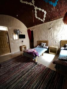 a room with a bed and a table and a rug at Adrar AbreQ-Bet AlkaRam in Siwa