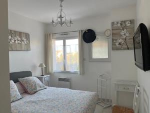Un dormitorio con una cama y un televisor. en Les hortensias, en Les Sables-dʼOlonne