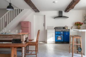 a kitchen with a table and a blue stove at Stable Cottage at Poxwell Manor in Poxwell