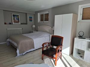 a bedroom with a bed and a chair at Le petit Clémenceau in Pessac