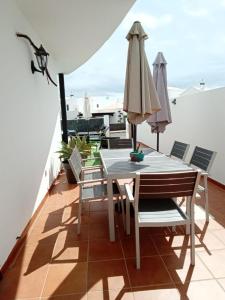 balkon ze stołem, krzesłami i parasolem w obiekcie Villa Erimar w mieście Playa Blanca