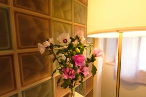 a vase of flowers sitting on a table next to a lamp at Vivi Lucca con "Madame Fannj" - Camera Viola in Lucca