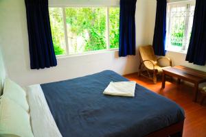 a bedroom with a bed with a blue blanket and two windows at HappyHuts at Green valley view in Kodaikānāl