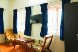 a dining room with blue curtains and a table and chairs at HappyHuts at Green valley view in Kodaikānāl