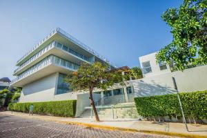 a white building with a tree in front of it at Spacious Magia Condo Steps to the beach & 5th Ave in Playa del Carmen