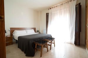 a bedroom with a bed and two chairs and a window at La Fonda del Arco in Guadix