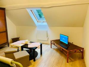 a living room with a table and a laptop on a desk at Studio au cœur des écuries in La Chapelle-Fortin