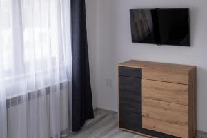 a room with a dresser and a tv and a window at Piatra Craiului Retreat in Zărneşti
