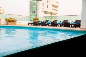 a pool with chairs and umbrellas in it at Travelers Orange Cartagena in Cartagena de Indias