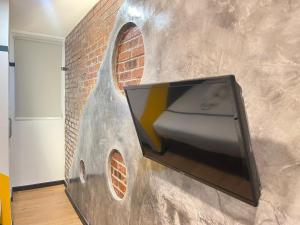 a tv on a wall with a brick wall at Seeds Hotel Klang Bayu Perdana in Klang