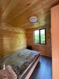 a large bed in a wooden room with a window at Jyrgallifе in Darkan +4 photos