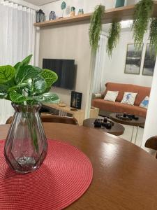 Un jarrón sobre una mesa con un posavasos rojo. en Apto 80m da Praia Grande vista mar!, en Governador Celso Ramos