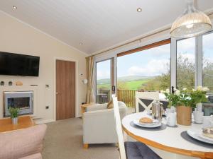 a living room with a table and a fireplace at Hideaway Lodge in Tintagel