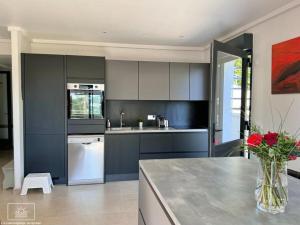 a kitchen with blue cabinets and a vase of flowers on a counter at La Gacélyte Piscine privée joli bas de villa in Carqueiranne