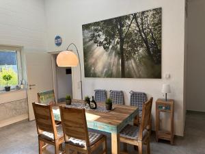 a dining room table with chairs and a painting on the wall at Komfortables Ferienhaus in Lichtenberg bei Hof im Frankenwald 400m vom See nahe Bad Steben in Lichtenberg