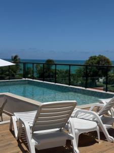 a group of chairs sitting next to a swimming pool at Rooftop Tamandaré - apto 106 in Tamandaré