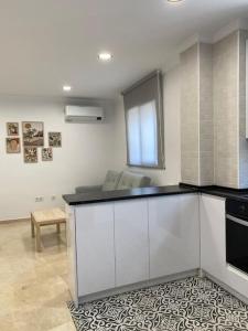 Una cocina con gabinetes blancos y una encimera negra. en Edifico Mañez Primero- Nuevo, 10 minutos Gibraltar, en La Línea de la Concepción 7 fotos más