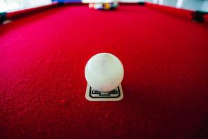 a white cue ball on a red table at El Principio Palace in Villa Cura Brochero