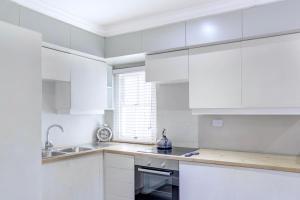 a white kitchen with white cabinets and a sink at Sandton Cozy Apartment in Johannesburg
