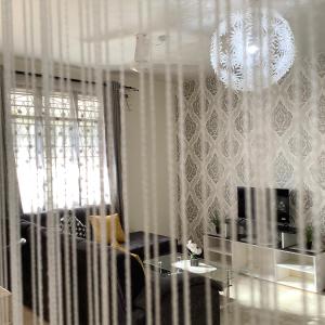 a living room with a chandelier and white curtains at Nguuni Sanctuary Home Stay in Mombasa