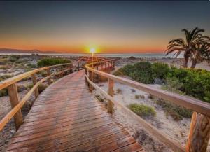 a wooden boardwalk leading to the beach at sunset at Villa Richmond in Gran Alacant