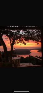 a sunset over the water with a table and a tree at Minas Em Marambaia in Rio de Janeiro