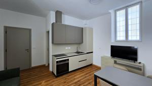 a kitchen with white cabinets and a flat screen tv at Bilocale centro storico in Novara