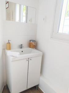 a white bathroom with a sink and a mirror at Petit Nid Urbain Proche RER, 25min Paris Centre Chambre privée et SDB privée indépendante in Stains
