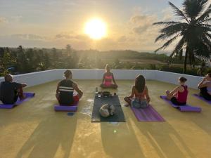 a group of people sitting on a roof watching the sunset at Casa Bela Vida in Fortim