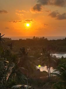 a sunset over the ocean with palm trees and a river at Casa Bela Vida in Fortim