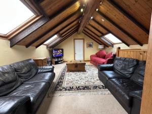 a living room with leather couches and a tv at The Old Vicarage in Berwick-Upon-Tweed