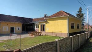 ein gelbes Haus mit einem Zaun davor in der Unterkunft Forest idyll in Repaš