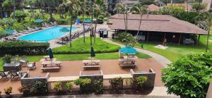 une vue aérienne d'une piscine avec des tables et des parasols dans l'établissement Pono Kai Resort #A101 - A Welcoming 2 Bdrm - 2 Bath, Private Beachfront Vacation Home, à Kapaa