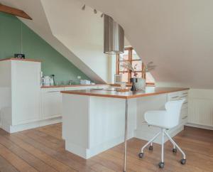 una cocina con armarios blancos y una silla blanca en Penthouse Downtown with 4 bedrooms and Harbour View, en Tórshavn