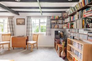 Cette chambre comprend un bureau, des chaises et des étagères. dans l'établissement Cozy One-Bedroom Cottage in Great Tey, à Great Tey