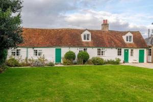 une maison blanche avec des volets verts et un jardin dans l'établissement Cozy One-Bedroom Cottage in Great Tey, à Great Tey