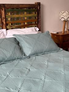 a bed with a green comforter and pillows at Hotel Boutique Canto da Seriema in Tiradentes