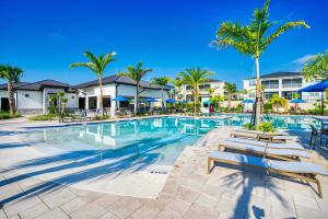 a pool at a resort with benches and palm trees at Stylish Home wPrivate Pool&Spa, near Disney in Davenport