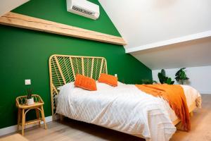 a bedroom with a green wall and a bed with orange pillows at Villa La Perle Bleue in Ebersheim +31 photos