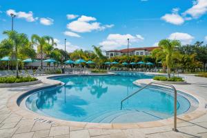 a pool at a resort with palm trees and umbrellas at Spacious Townhome wPatio Garage Sleeps10 in Orlando